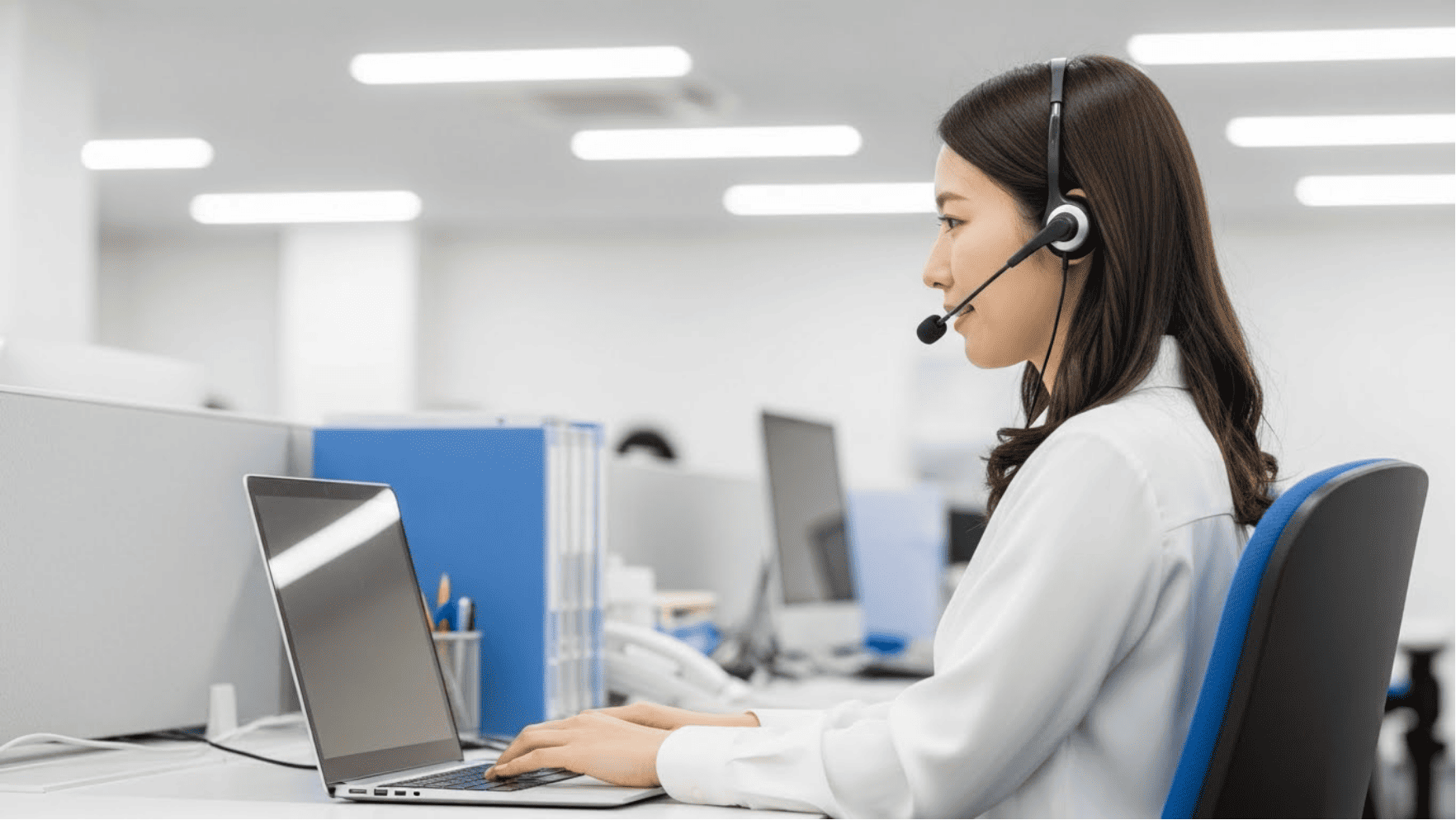 ヘッドセットをつけてパソコンに向かうオンライン事務スタッフの女性の写真